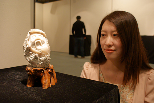 京都市国際交流会館でめのうの彫刻の展示会を開いたKCGI学生の張さん。作品は自信作「楽」