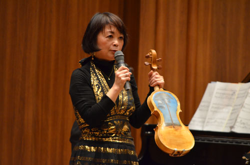 Kimiko Nakazawa shows off a violin she made from driftwood that had been turned into rubble.The reverse side depicts the 