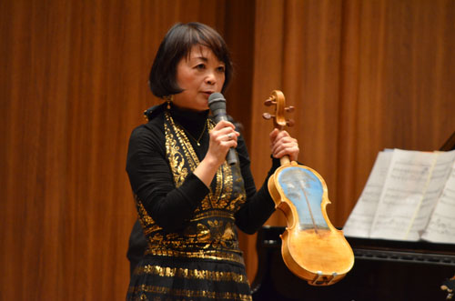 がれきとなった流木から製作したヴァイオリンを披露する中澤きみ子さん。裏面には東日本大震災による津波に耐え,被災地の人たちの支えとなってきた陸前高田市の「奇跡の一本松」が描かれています