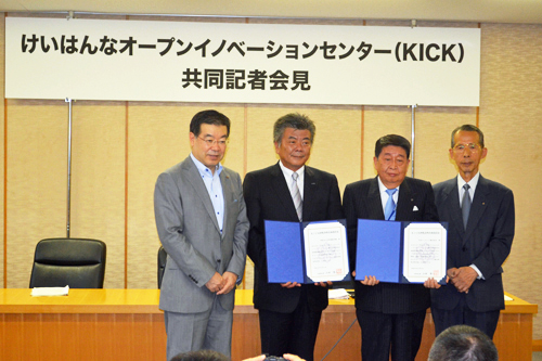 President Wataru Hasegawa (second from left) poses for a commemorative photo with reporters after the Cyber Kyoto Research Institute project received the first approval from the Kyoto Prefectural Government for the Keihanna Open Innovation Center research utilization plan.Kyoto Governor Keiji Yamada on the far left and Kyoto Prefectural Councilor Makoto Nagao on the far right.