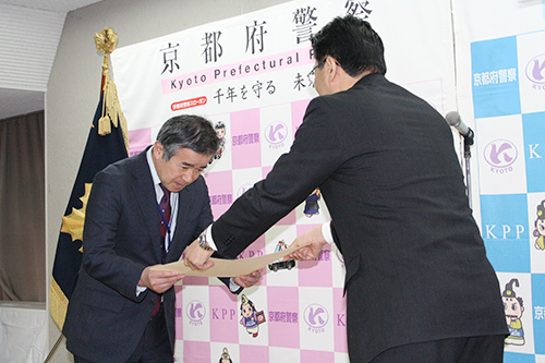 Professor Shozo Naito receives a letter of appreciation from Takayuki Sakai, Chief of Kyoto Prefectural Police Headquarters