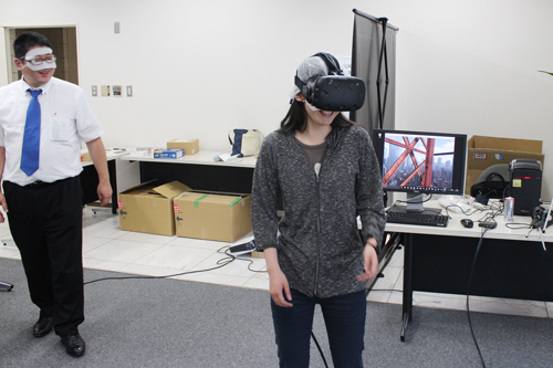 A view of the VR booth.Wearing VR goggles, participants actually experience VR space.The students were amazed at the high places, saying, 