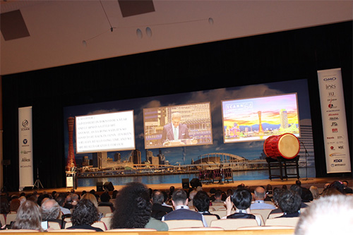 メインホール会場左側スクリーンではスピーチが文字表示される。