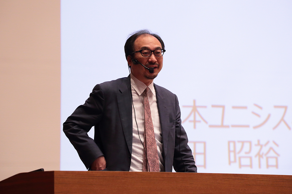 京都情報大学院大学(KCGI)の創立17周年記念式典で記念講演する日本ユニシス株式会社フェロー・総合技術研究所所長(CTO)の羽田昭裕様(2020年11月6日,KCGI京都駅前サテライト大ホール)