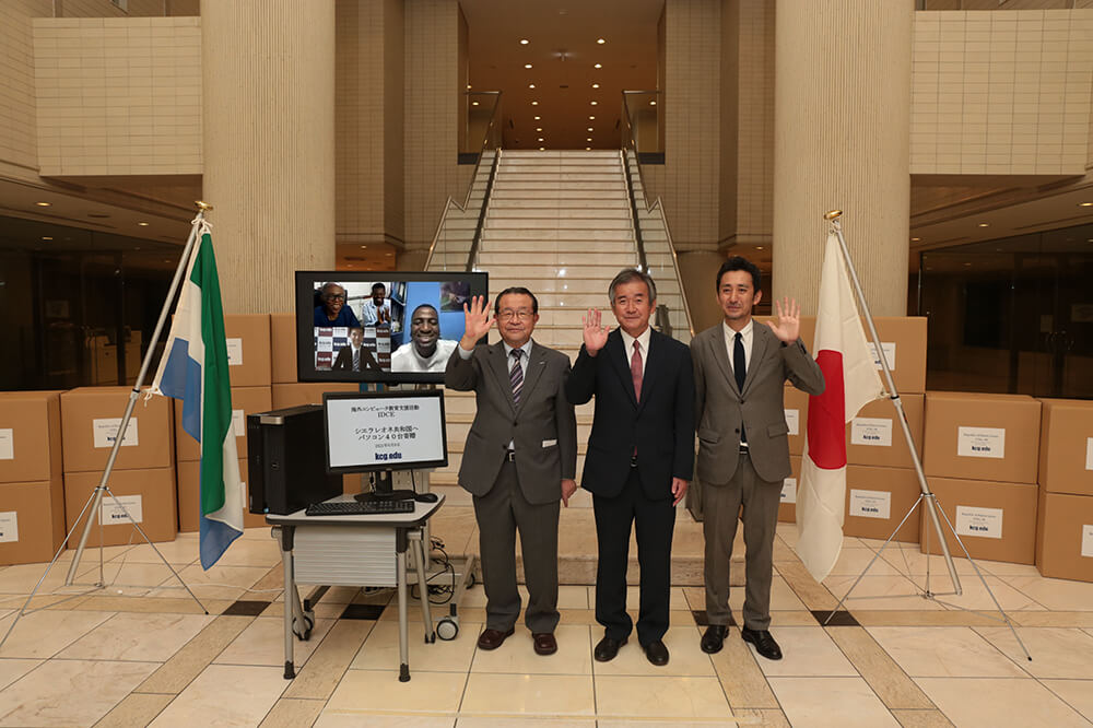 Mr. Taylor, President of University of Management and Technology, Republic of Sierra Leone, Mr. Terashita, Principal of KCG Kyoto Ekimae School, Mr. Naito, Principal of KCG Kamogawa School and other participants pose for a commemorative photo in front of the computer to be donated.