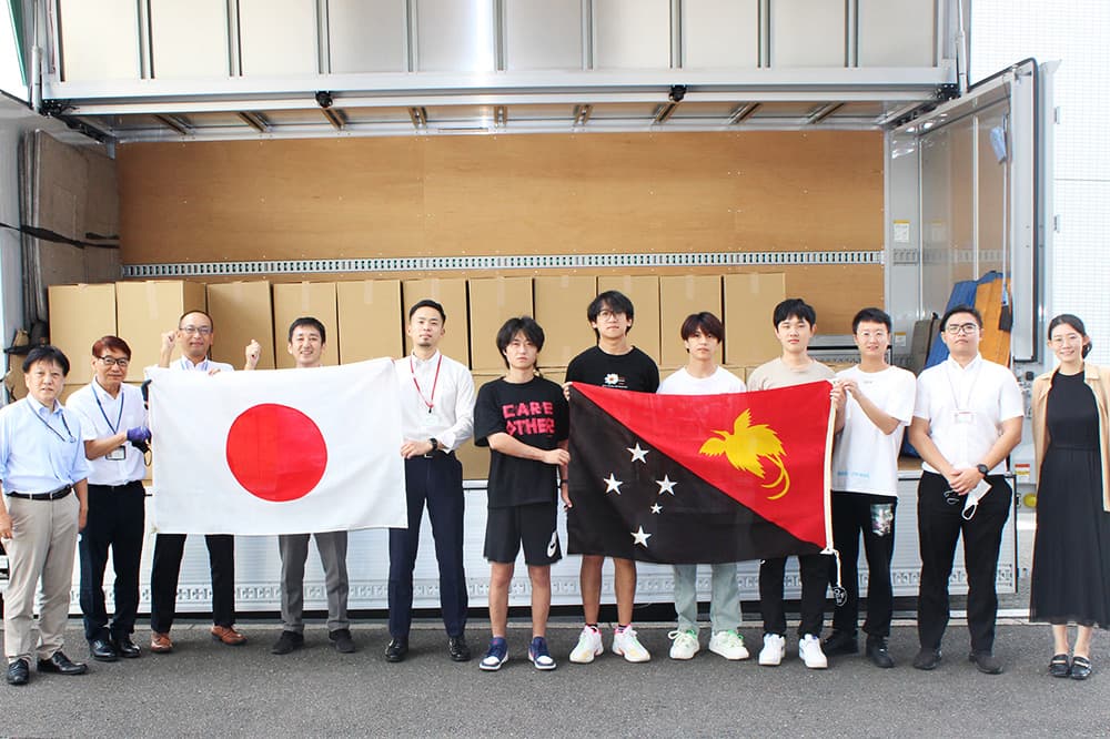 Students and faculty members who helped load the PCs pose for a commemorative photo in front of a truck loaded with PCs leaving Kyoto Computer Gakuin Kyoto Ekimae Campus on October 3, 2023.