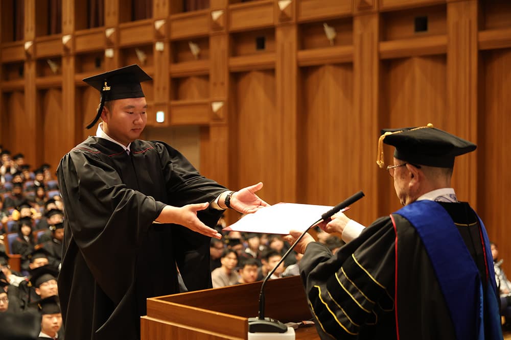 President Yoichi Terashita (left) presents degrees to representatives of KCGI alumni.