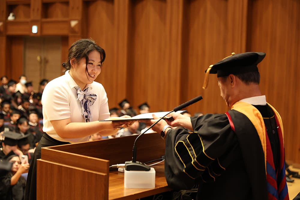 Noboru Takahiro, Principal of Rakuhoku School, presents diplomas and certificates to representatives of KCG graduates.