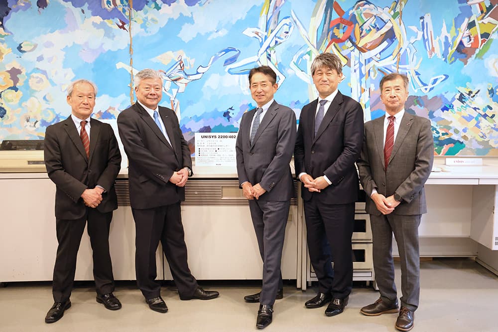 UNISYS2200/402の前で記念撮影。中央が齊藤社長，右から２番目が佐藤執行役員・関西支社長（2026年4月2日， KCGコンピュータミュージアム）