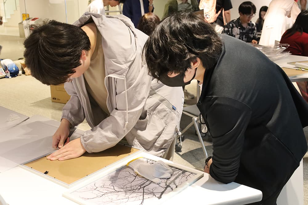 丁寧に作品を額に入れていきます