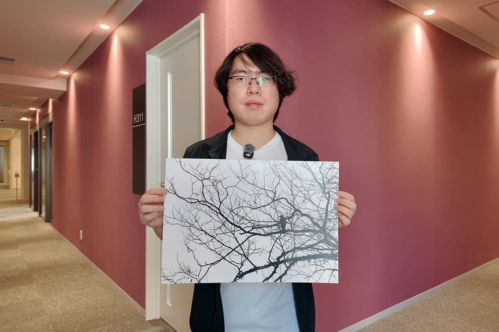 自身の作品を手にしたKCGIの王さん。「自分の内面を反映している一枚です」